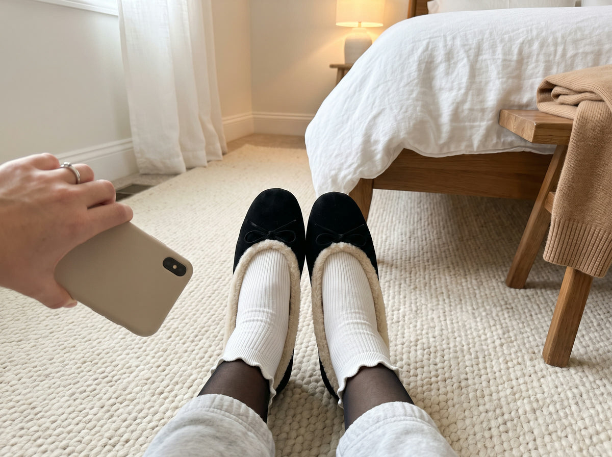 Trying on the Courchevel Flat in Black at home on a clean rug, with white ruffle socks over sheer black tights