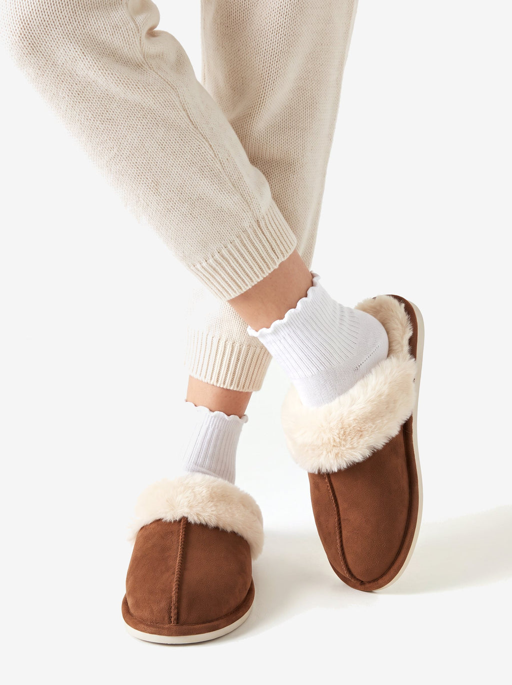 The Courchevel Slipper in Chestnut, ankles crossed, fur collar all the way around