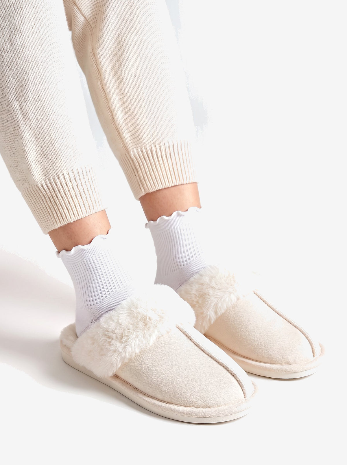 The Courchevel Slipper in Cream, worn with white ruffle socks