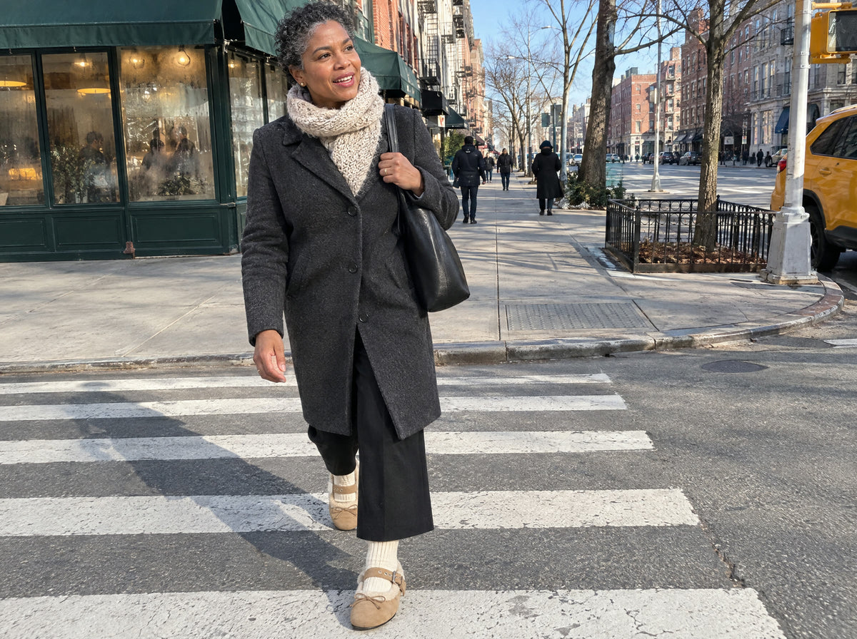 A woman crosses a dry city street on a cold sunny morning in the New York Mary Jane in Sand with ivory wool socks